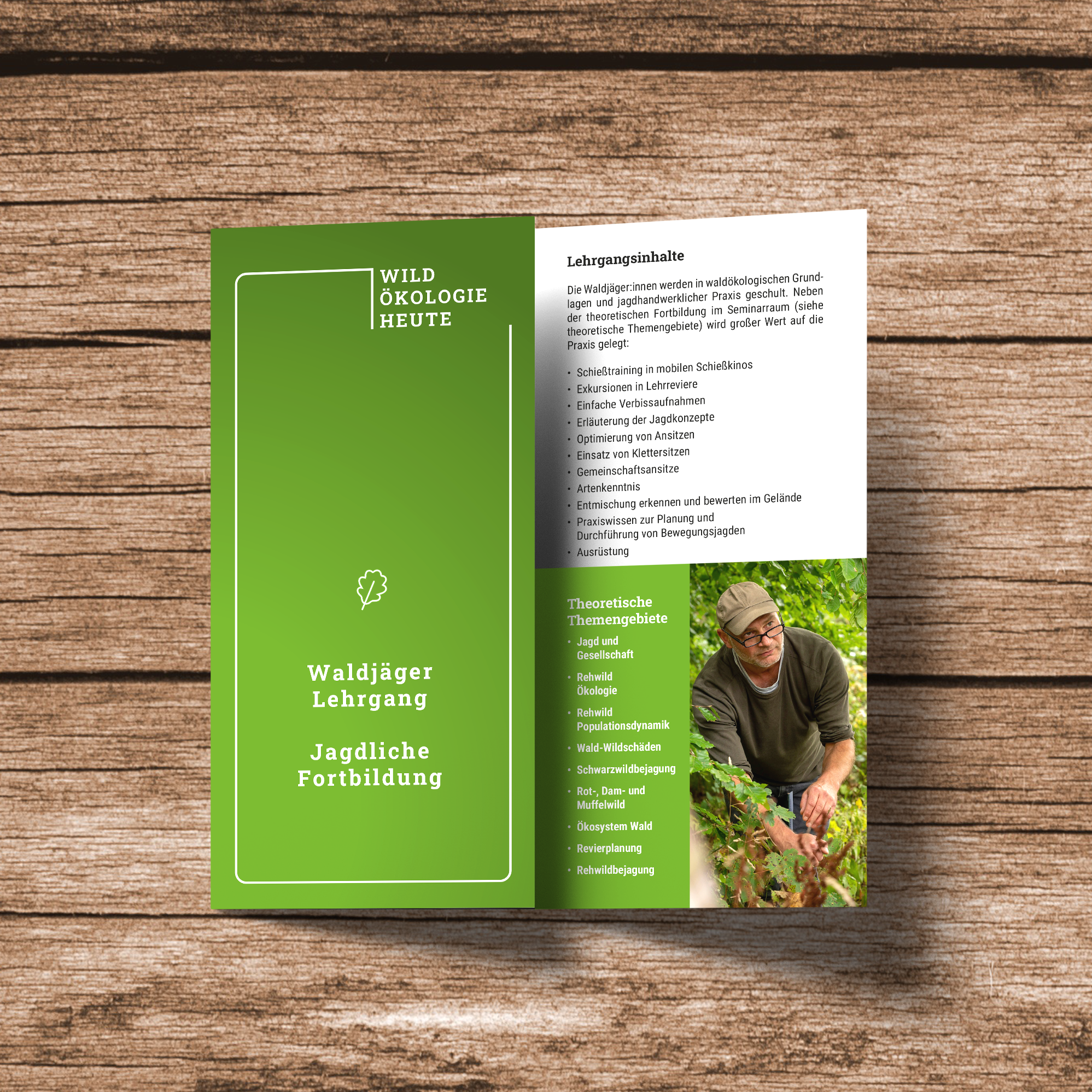 Aufgeklappter grüner Flyer „Wildökologie Heute – Waldjäger Lehrgang, Jagdliche Fortbildung“ auf Holzuntergrund
