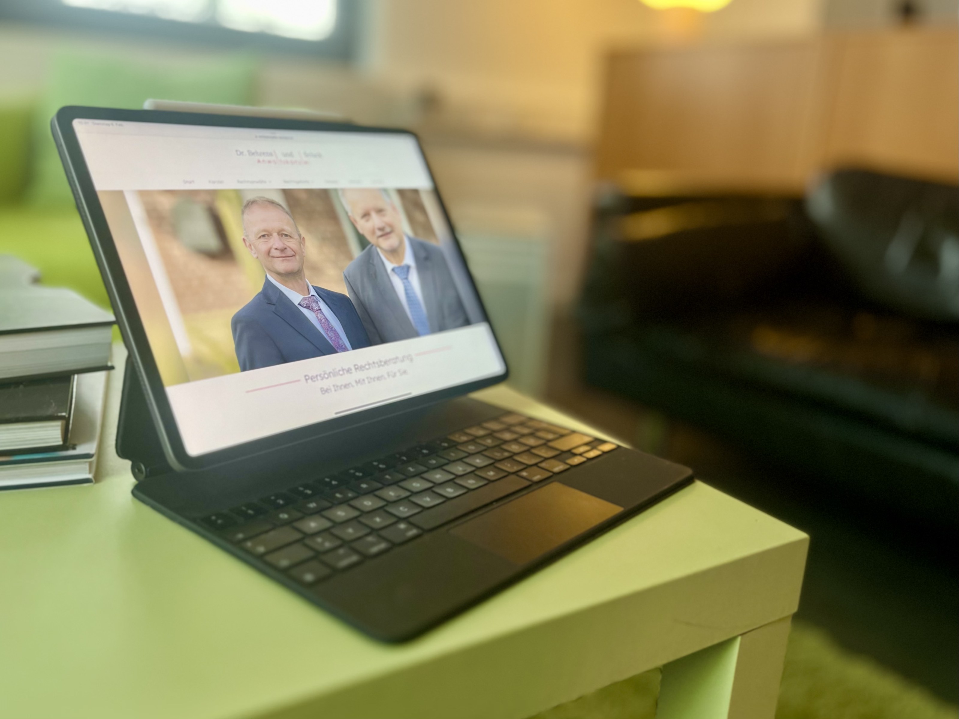 Tablet mit der Website einer Anwaltskanzlei: zwei Anwälte im Anzug, darunter „Persönliche Rechtsberatung“